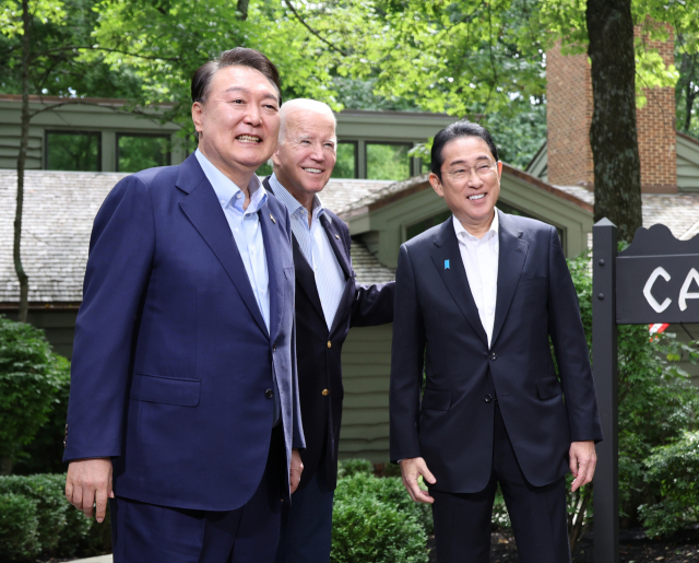 윤석열 대통령과 조 바이든 미국 대통령, 기시다 후미오 일본 총리가 18일(현지시간) 워싱턴DC 인근 미국 대통령 별장인 캠프 데이비드에서 열린 한미일 정상회의를 앞두고 로렐 로지 앞에서 기념 촬영을 하고 있다. 연합뉴스