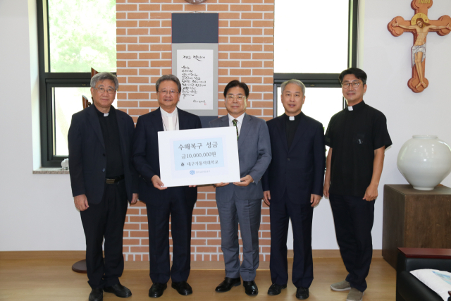 대구가톨릭대 성한기 총장(사진 가운데)이 호우 피해 이웃을 돕는 데 써달라며 18일 수해 복구 성금을 천주교 안동교구에 기탁했다.