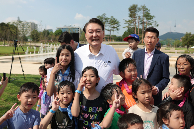 윤석열 대통령이 26일 서울 용산어린이정원 내 조성된 분수정원에서 열린 다둥이가족 초청행사에 깜짝 방문, 어린이들과 기념사진을 찍고 있다. 연합뉴스