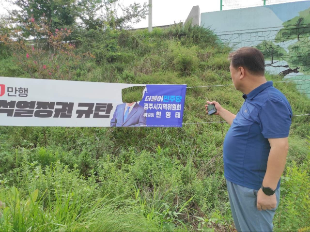한영태 더불어민주당 경주시지역위원장이 정당 현수막 일부가 훼손된 것을 지켜보고 있다. 한영태 위원장 제공