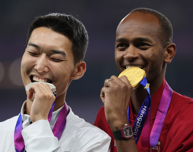 중국 항저우 올림픽 스포츠센터에서 열린 2022 항저우 아시안게임 남자 높이뛰기 결선에서 2m33을 넘으며 은메달을 차지한 우상혁이 시상대에 올라 금메달을 딴 카타르의 무타즈 에사 바르심과 기념사진을 찍고 있다. 연합뉴스
