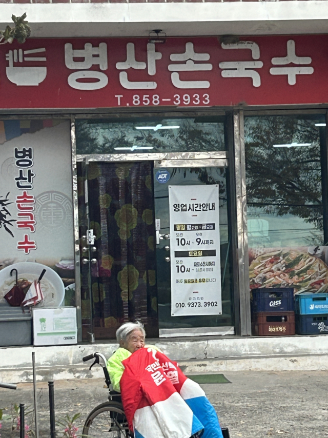 27일 오후 3시쯤 김수행(94) 할머니가 안동 풍천면 한 음식점 앞에서 휠체어를 타고 윤 대통령이 탑승한 차량이 지나가기를 기다리고 있다. 독자 제공