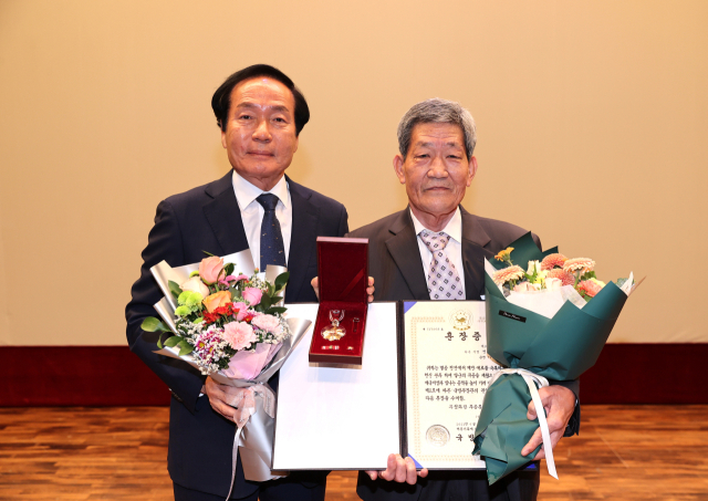 6·25전쟁 참전용사인 고(故) 전주호 일병의 아들인 전수원(오른쪽) 씨가 김주수 의성군수로부터 화랑무공훈장을 전달받고 기념촬영을 하고 있다. 의성군 제공
