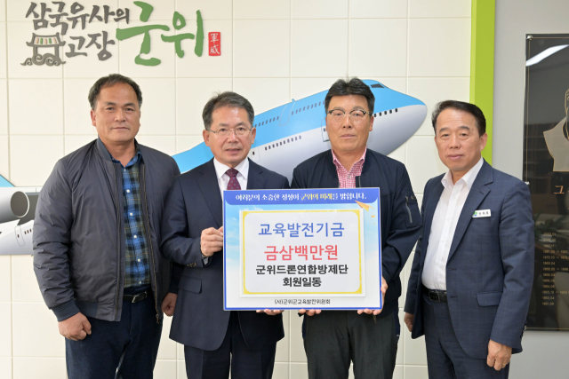 대구시 군위드론방제단이 군위군에 교육발전기금을 기탁하고, 김진열 군수와 기념 사진을 촬영하고 있다. 군위군 제공