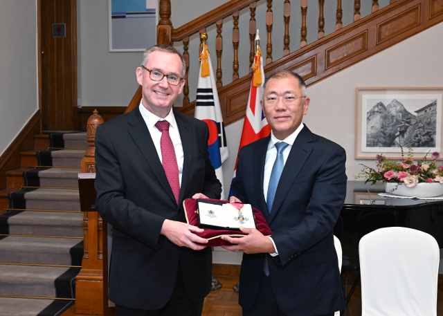 정의선 현대자동차그룹 회장이 지난 14일 서울 중구 주한 영국 대사관에서 대영제국 지휘관 훈장을 들고 콜린 크룩스 주한 영국 대사와 기념 촬영하고 있다. 연합뉴스