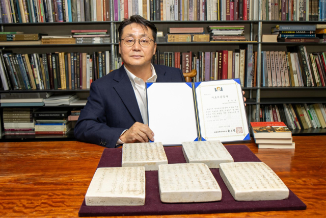 전윤수 중국미술연구소 대표가 한국국학진흥원에 기증한 약봉 김극일 선생의 지석 앞에서 기증서를 들고 기념 촬영을 하고 있다. 한국국학진흥원 제공