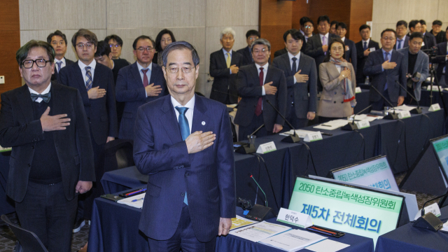 한덕수 국무총리가 23일 오전 서울 마포구 누리꿈스퀘어에서 열린 2050 탄소 녹색 성장위원회 5차 전체 회의에 참석해 민간위원들과 국기에 경례하고 있다. 연합뉴스