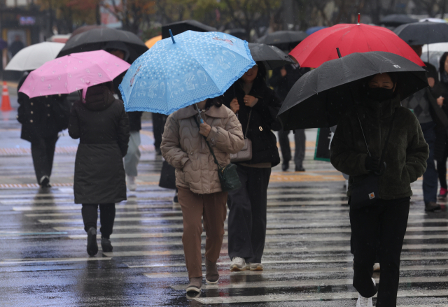 16일 오전 서울 광화문광장 인근에서 갑자기 비가 내리자 시민들이 우산을 쓰고 이동하고 있다. 연합뉴스