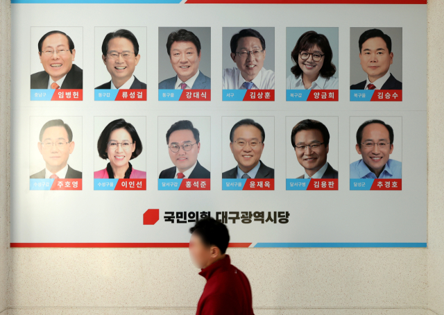 27일 국민의힘 대구시당 벽에 붙은 지역구 국회의원 사진 앞으로 당직자가 지나가고 있다. 국민의힘은 이날 내년 총선을 앞두고 고강도로 실시한 당무감사 결과와 함께 대략적인 하위권 컷오프 비율 등을 발표했다. 김영진 기자 kyjmaeil@imaeil.com