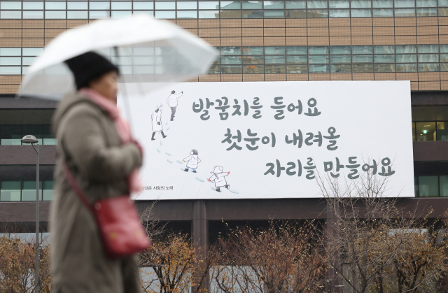 기온이 영상권을 회복한 27일 오전 서울 종로구 광화문광장 인근에 비가 내리자 시민이 비를 피하고 있다. 연합뉴스