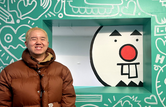 샨티 캐리커쳐 대표 서상준 작가가 자신의 캐리커쳐 앞에서 환하게 웃고 있다.