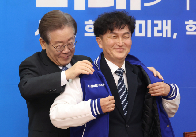 18일 국회에서 열린 더불어민주당 인재영입식에서 이재명 대표가 세번째 영입 인재인 류삼영 전 총경에게 당 점퍼를 입혀주고 있다. 연합뉴스