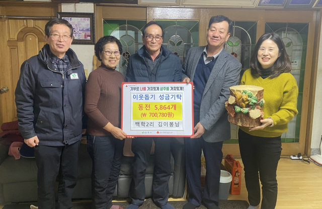 5년 동안 모은 동전 5천800여개를 기부한 김이봉(가운데)씨가 박광호 모서면장 등과 기념촬영을 하고 있다. 상주시 제공