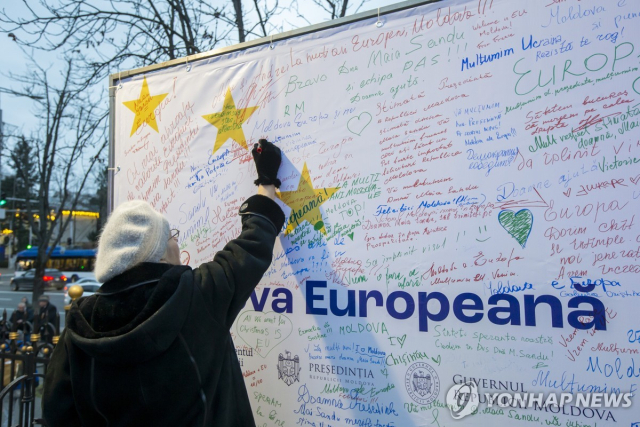 유럽연합(EU) 가입을 위한 협상 개시가 확정된 것을 환영하는 글을 현수막에 적어 넣는 몰도바 여성 [EPA 연합뉴