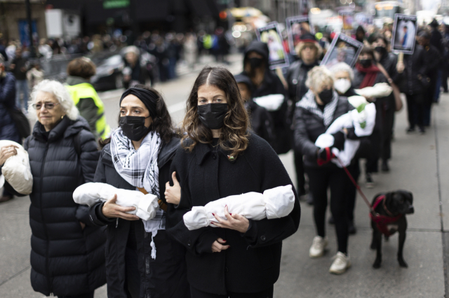지난달 28일(현지시간) 미국 뉴욕에서 이스라엘과 팔레스타인 무장 정파 하마스 간 전쟁으로 사망한 사람들을 추모하는 집회가 열린 가운데 참가자들이 어린이 희생자를 상징하는 인형을 들고 가고 있다. 하마스가 통치하는 가자지구 보건부에 따르면 개전 이후 가자지구에서 2만명 이상이 숨졌으며 사망자 중 상당수는 여성과 어린이다. 연합뉴스