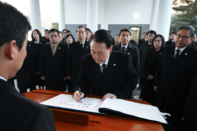 윤석열 대통령이 2024년 새해 첫날인 1일 서울 동작구 국립서울현충원에서 현충탑에 참배한 뒤 방명록을 남기고 있다. 연합뉴스