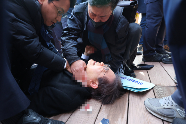 더불어민주당 이재명 대표가 2일 부산 가덕도 신공항 부지를 둘러본 후 기자들과 문답을 진행하던 중 왼쪽 목 부위에 습격을 당해 피를 흘린 채 쓰러져 있다. 연합뉴스