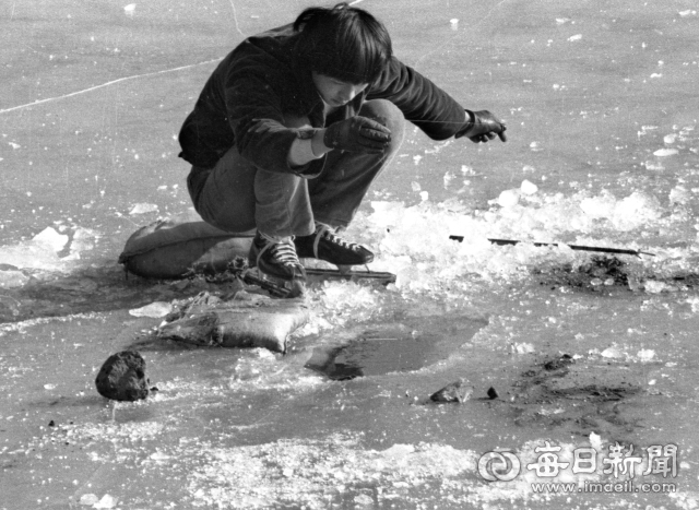 1977년 1월 23일 동촌 금호강에서 스케이트를 타던 한 청년이 빙판 위에서 얼음낚시를 하고 있다. 사진=매일아카이빙센터