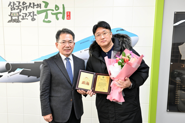 김진열 대구 군위군수가 대구 편입 등에 기여한 김용판 국회의원실 김도훈(오른쪽) 수석보좌관에게 명예군민증을 수여하고, 기념 사진을 촬영하고 있다. 군위군 제공