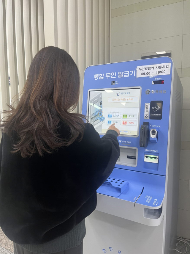 민원인이 기장군청 종합민원실에 설치된 대법원통합무인발급기에서 민원서류를 발급하고 있다. [사진=기장군]