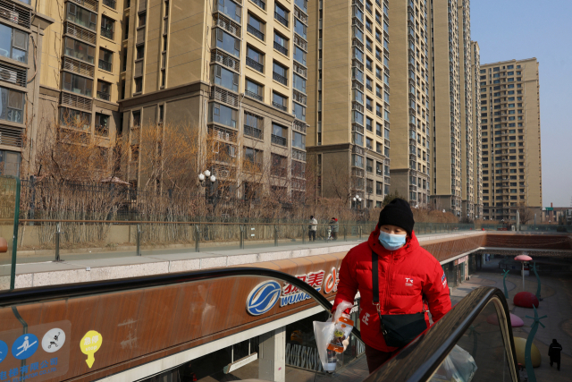 29일 중국 베이징에서 한 여성이 부동산 개발업체 헝다그룹이 지은 주거용 건물 인근에 설치된 에스컬레이터를 올라가고 있다. 이날 홍콩고등법원은 빚더미에 앉은 헝다그룹에 청산을 명령했다. 연합뉴스