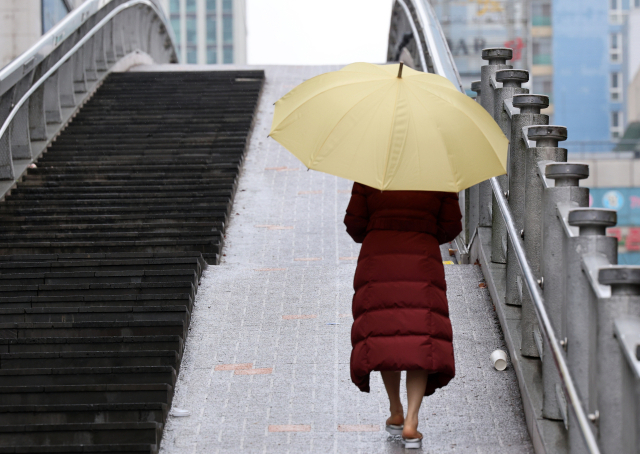 18일 오전 광주 서구 치평동에서 한 시민이 내리는 겨울비에 우산을 쓰고 걷고 있다. 연합뉴스
