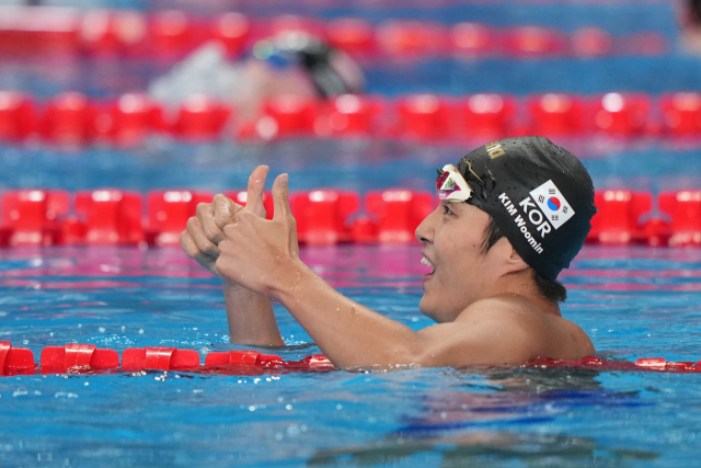 한국의 김우민이 12일 카타르 도하에서 열린 2024 도하 국제수영연맹 세계선수권대회 경영 남자 자유형 400m에 출전해 1위로 터치패드를 찍은 뒤 기뻐하고 있다. 연합뉴스