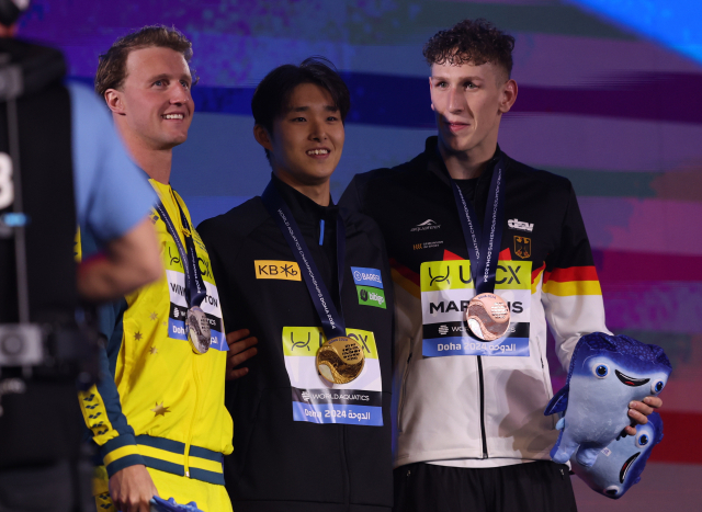 한국의 김우민(가운데)이 12일 카타르 도하에서 열린 2024 도하 국제수영연맹 세계선수권대회 경영 남자 자유형 400m에 출전해 금메달을 목에 건 뒤 기념 촬영을 하고 있다. 연합뉴스