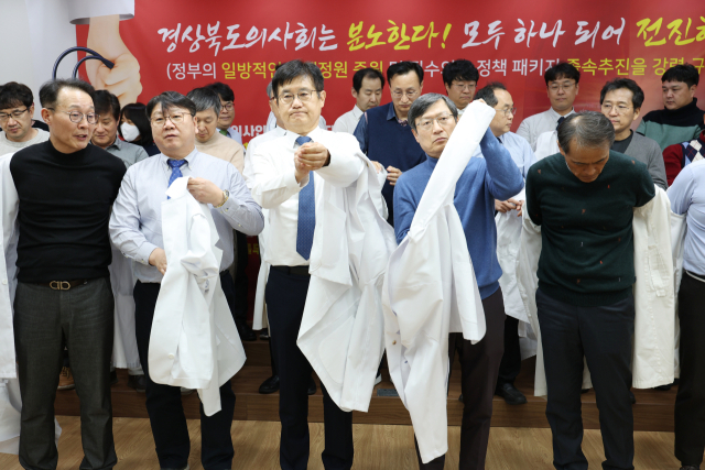 경북도의사회 이우석 회장 등 도의사회 소속 의사들이 15일 오후 7시 경북도의사회관에서 정부의 의대 정원 확대 정책에 반발하는 규탄대회를 열고 의사가운 탈의식을 진행하고 있다. 연합뉴스