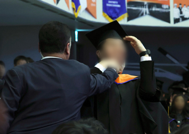 지난달 16일 대전 유성구 한국과학기술원(KAIST)에서 열린 2024년 학위수여식에서 한 졸업생이 윤석열 대통령이 축사를 할 때 R＆D 예산과 관련해 자리에서 일어나 대통령을 향해 항의를 하던 중 제지를 당하고 있다. 연합뉴스