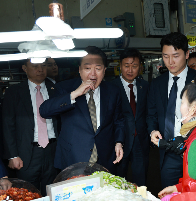 윤석열 대통령이 22일 경남 창원시 마산합포구 마산어시장을 찾아 젓갈가게에서 호래기(꼴뚜기)를 맛보고 있다. 연합뉴스
