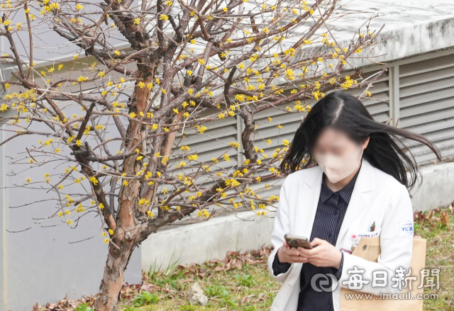 전공의들의 집단 이탈사태가 4주째를 넘어선 12일 대구의 한 대학병원에 핀 산수유 앞으로 의료진이 이동하고 있다. 안성완 기자 asw0727@imaeil.com