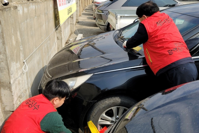 창녕군 담당 공무원들이 체납차량의 납세를 위해 바퀴잠금장치를 다는 모습. 창녕군 제공