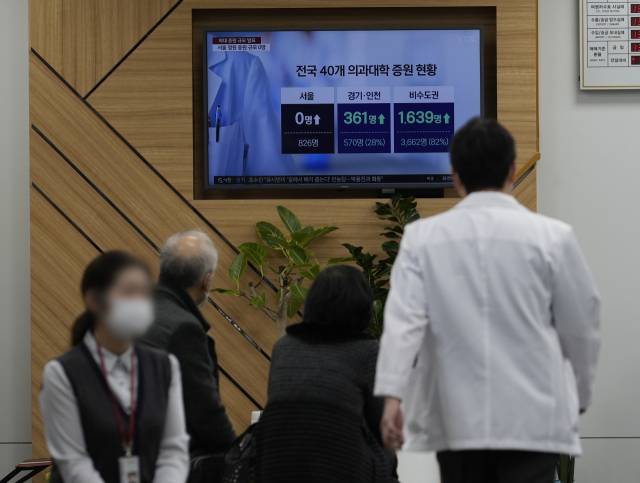 정부가 의대 증원 배분 발표를 한 20일 대구 한 상급종합병원에서 발걸음을 옮기는 의사 앞으로 시민들이 관련 뉴스를 보고 있다. 김영진 기자 kyjmaeil@imaeil.com