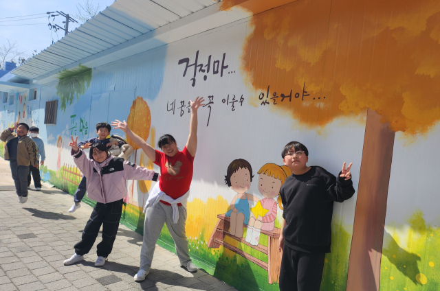 가천초교 학생들이 자신들이 그린 학교 담장 벽화 앞에서 환호하고 있다. 가천초교 제공