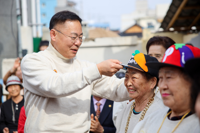 김재욱 칠곡군수(사진 왼쪽)가 다섯 번째로 창단 한 할매래퍼 그룹 '텃밭 왕언니' 맴버들에게 모자를 씌워 주고 있다. 칠곡군 제공