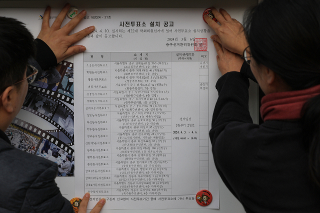 제22대 국회의원 선거를 16일 앞둔 25일 오전 서울 중구 을지로동주민센터 앞 게시판에서 주민센터 직원이 사전투표소 설치 공고를 게시하고 있다. 연합뉴스