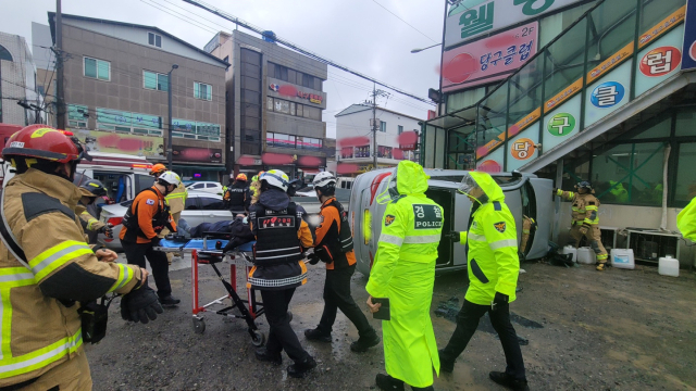 지난 3일 오후 포항시 남구 해도동 한 도로에서 상가건물 계단과 충돌해 전도된 택시에서 구조대원들이 운전자를 구조하고 있다. 포항남부소방서 제공.