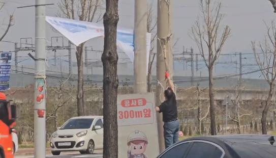 국민의힘 충주시의원이 민주당 현수막을 낫으로 철거하는 모습. 민주당 충북도당 제공