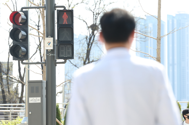 전공의 집단행동이 이어지고 있는 9일 오전 서울 시내 한 대형병원에서 한 의료 관계자가 횡단보도 신호를 기다리고 있다. 연합뉴스