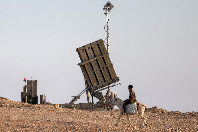 이스라엘을 겨냥한 이란의 보복 공습으로 중동에 전운이 고조되고 있다. 14일(현지시간) 이스라엘 아이언돔 방공 미사일 시스템 부근에 한 소년이 당나귀를 타고 지나가고 있다. AFP 연합뉴스