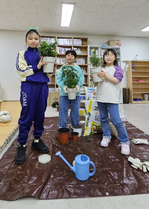 인성 교실에서 화분을 키우는 아이들의 모습. 화분마다 삐뚤빼뚤 써진 저마다의 이름을 보면 아이들이 얼마나 사랑을 주며 가꾸고 있는지 눈에 선하다. 화분이 쑥쑥 자라듯 아이들의 인성도 쑥쑥 자랄 것이다.