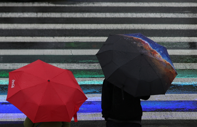 전국적으로 비가 내린 지난달 24일 오전 서울시청 인근에서 시민들이 우산을 쓴 채 신호가 바뀌기를 기다리고 있다. 연합뉴스