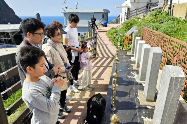 4일 독도 동도 정상에 설치된 위령비를 찾은 고 주재원 경비대장의 가족이 주 대장의 명복을 빌고 있다. 사진 앞쪽부터 주 대장의 손자 주예성(재만 씨 아들), 장남 주재현, 아내 장노식, 며느리 황은하(재현 씨 아내), 손녀 주예린(재만 씨 딸), 손자 주예준(재현 씨 아들). 주재만 씨 촬영