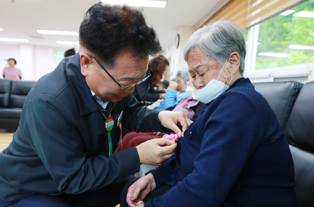 손병복 울진군수가 공무원들이 직접 만든 카네이션을 어르신들에게 달아 드리고 있다. 울진군 제공