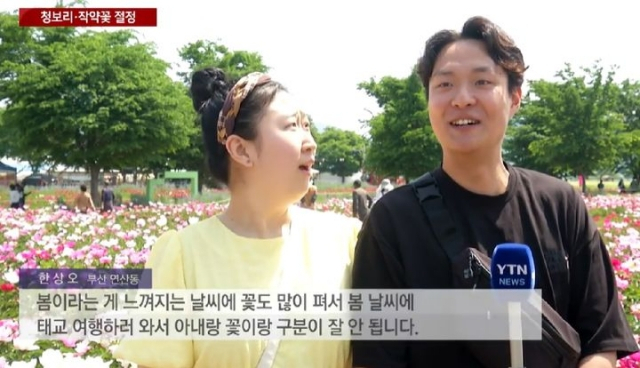 한 남성이 뉴스 인터뷰 도중 아내를 향해 달달한 멘트를 하자, 아내가 화들짝 놀라고 있다. YTN뉴스 방송화면 캡처