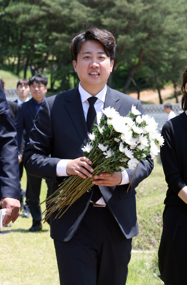 15일 오전 광주 북구 국립 5·18 민주묘지에서 개혁신당 이준석 대표와 당선인들이 국화를 들고 이동하고 있다. 이 대표는 경남 김해에서 재배한 국화 1천송이를 직접 공수해 995기에 달하는 개별 묘지에 헌화·참배했다. 연합뉴스