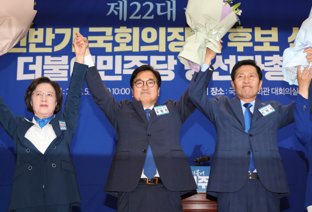 더불어민주당 국회의장 후보로 선출된 우원식 후보(가운데)와 국회부의장 후보로 선출된 이학영 후보(오른쪽)가 16일 오전 국회 의원회관에서 열린 제22대 전반기 국회의장단 후보 선출을 위한 당선자 총회에서 꽃다발을 들고 두 팔을 들어올리고 있다. 연합뉴스