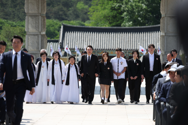 윤석열 대통령이 18일 광주시 북구 국립5·18민주묘지에서 열린 제44주년 5·18민주화운동 기념식에 참석해 5·18 유가족 대표들과 함께 입장하고 있다. 연합뉴스