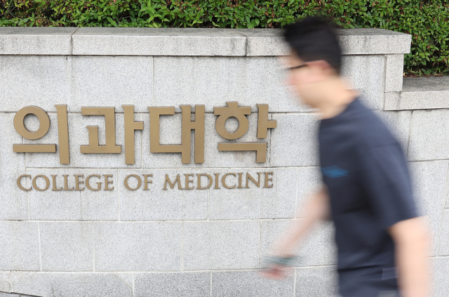 27년 만의 의대 입학정원 증원이 확정된 24일 시민들이 서울 시내 한 의과대학 인근을 지나고 있다. 한국대학교육협의회는 이날 대입전형위원회를 열고 각 대학이 제출한 2025학년도 대입전형 시행계획 변경 사항을 심의·확정했다. 연합뉴스